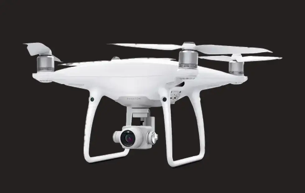 A white dji phantom quadcopter on a black background.